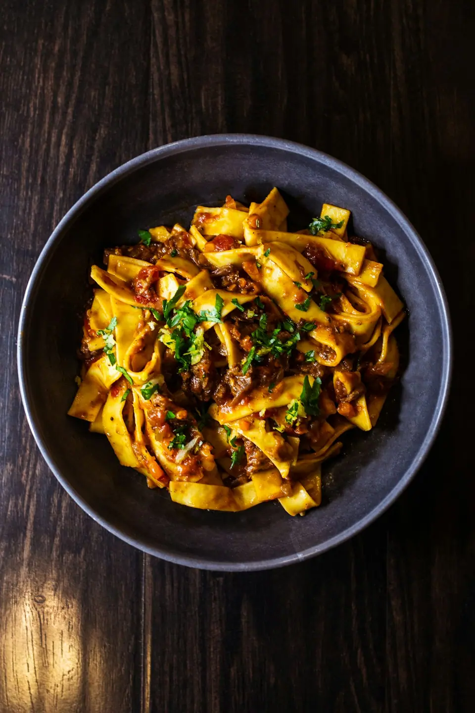 A bowl of wide ribbon pasta with beef ragù and parsley