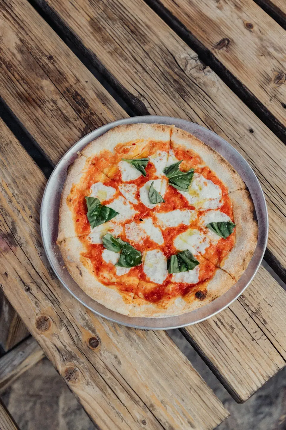 A margherita pizza seen from above on a wooden table