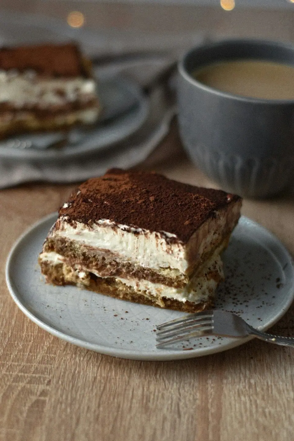A square of tiramisu on a plate with a fork